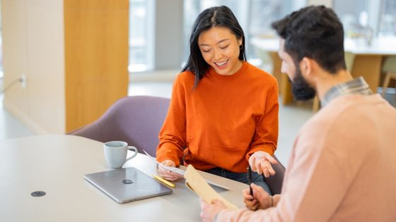 Two nonprofit team members reviewing a report together in a modern office setting, discussing donor engagement and impact.