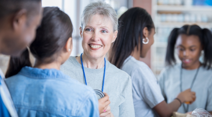 Smiling older woman stands among volunteers, representing gratitude, connection, and nonprofit donor stewardship in action.